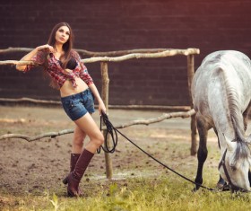 Beautiful girl holding horse and fence background