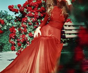 Beautiful woman sitting on a bench in fashionable photos in the flowers