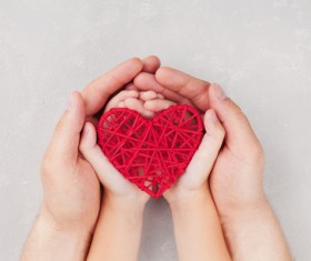 Big hand and small hands holding red weave heart-shaped Stock Photo