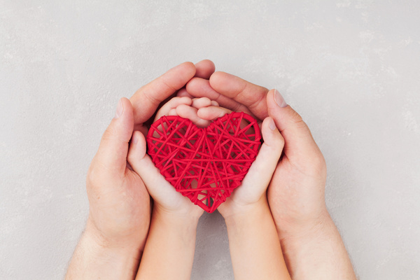 Big hand and small hands holding red weave heart shaped Stock Photo