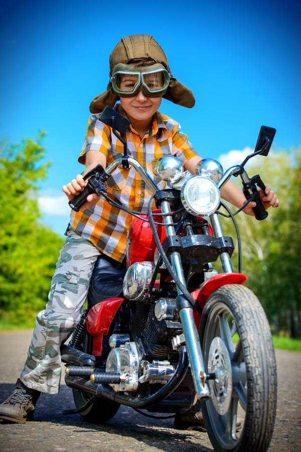 Boy riding a motorcycle with blue sky background