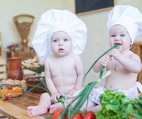 Cook costume Baby Eating Onion Stock Photo
