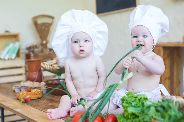 Cook costume Baby Eating Onion Stock Photo