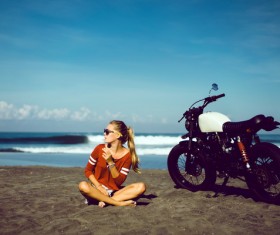 Girl sitting on the beach with a motorcycle Stock Photo