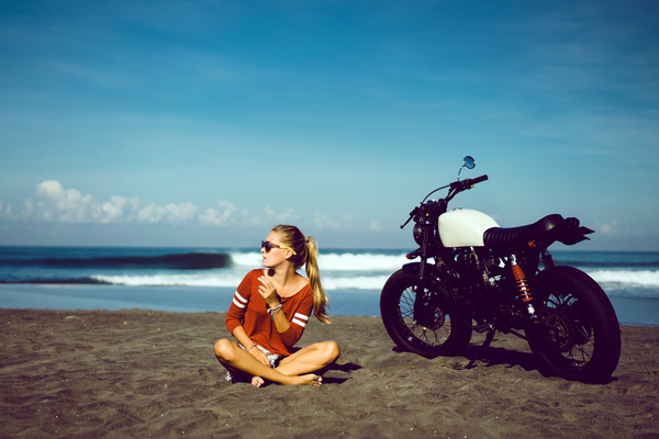 Girl sitting on the beach with a motorcycle Stock Photo