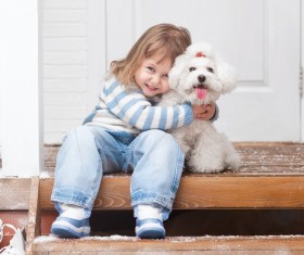 Girl sitting on the promenade with arms around white puppy Stock Photo