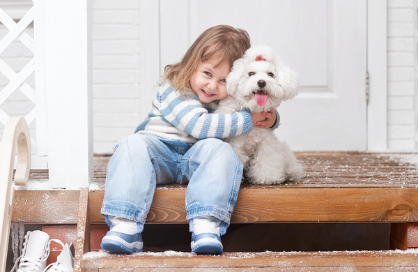 Girl sitting on the promenade with arms around white puppy Stock Photo