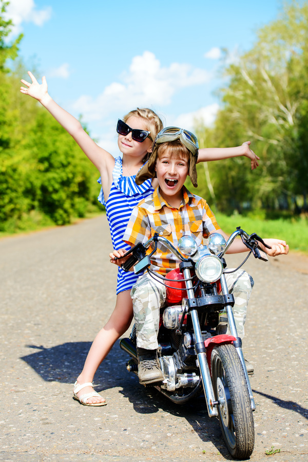 Happy kids go on a journey on a motorcycle on a bright sunny day