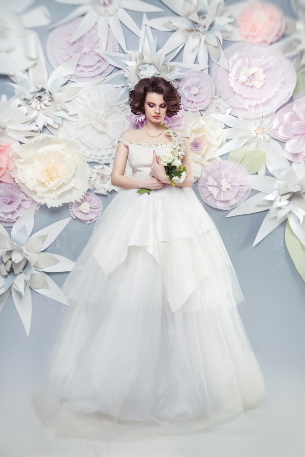 Low head holding flowers Happy woman wearing a wedding dress with fake background