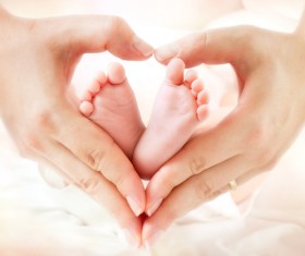 Mother heart-shaped hands with baby feet Stock Photo