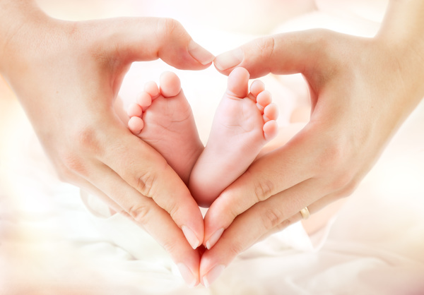 Mother heart shaped hands with baby feet Stock Photo