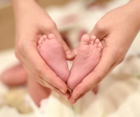 Mother’s hand holding the baby’s feet Stock Photo