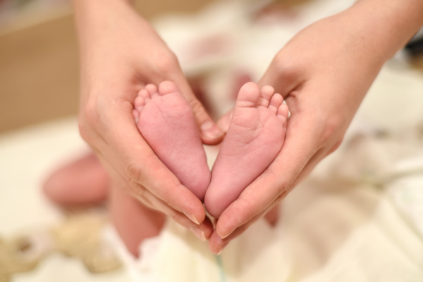 Mother's hand holding the baby's feet Stock Photo