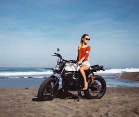 Pretty girl riding a motorcycle with a sea background Stock Photo