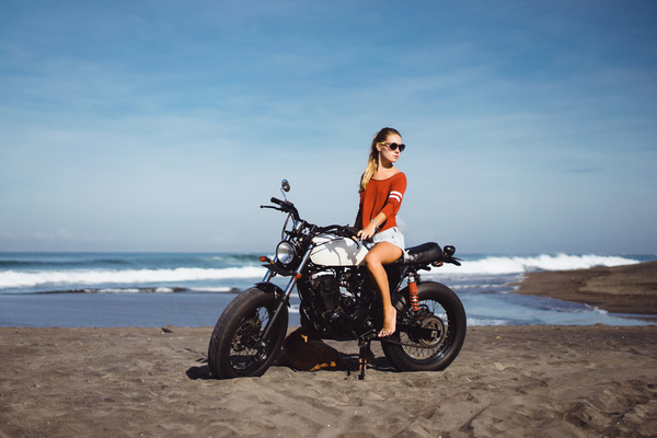 Pretty girl riding a motorcycle with a sea background Stock Photo