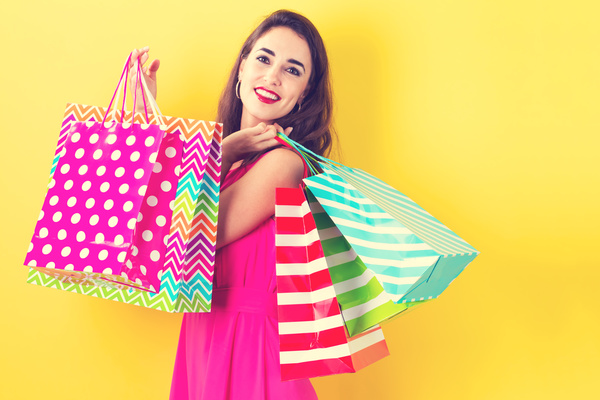 Pretty happy woman holding shopping bags on a yellow background