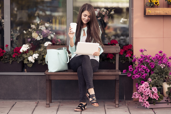 Sitting on a bench in front of a flower shop to play a girl on the computer coffee