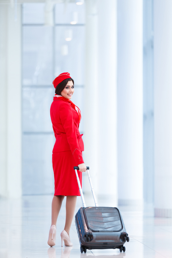Smiling flight attendants dragging the suitcase turned Stock Photo