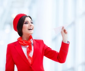 Smiling stewardess holding paper airplane Stock Photo