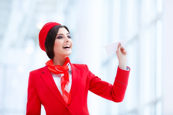 Smiling stewardess holding paper airplane Stock Photo