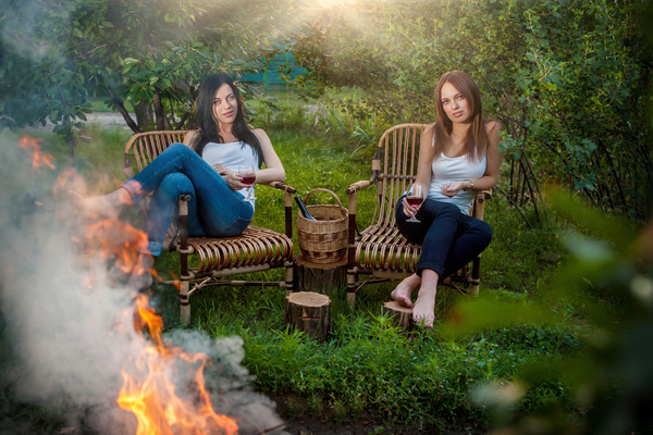 Summer holidays and vacation - girls with red wineglasses near bonfire