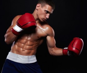 The young male athlete kickboxing on a black background