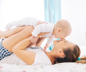 The young mother holding a baby playing in bed