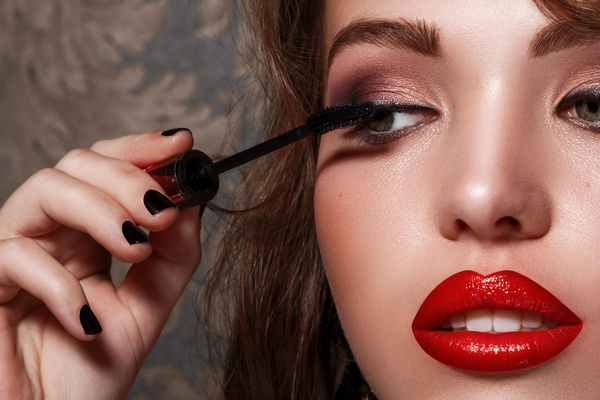 Women with red lips brush eyelashes