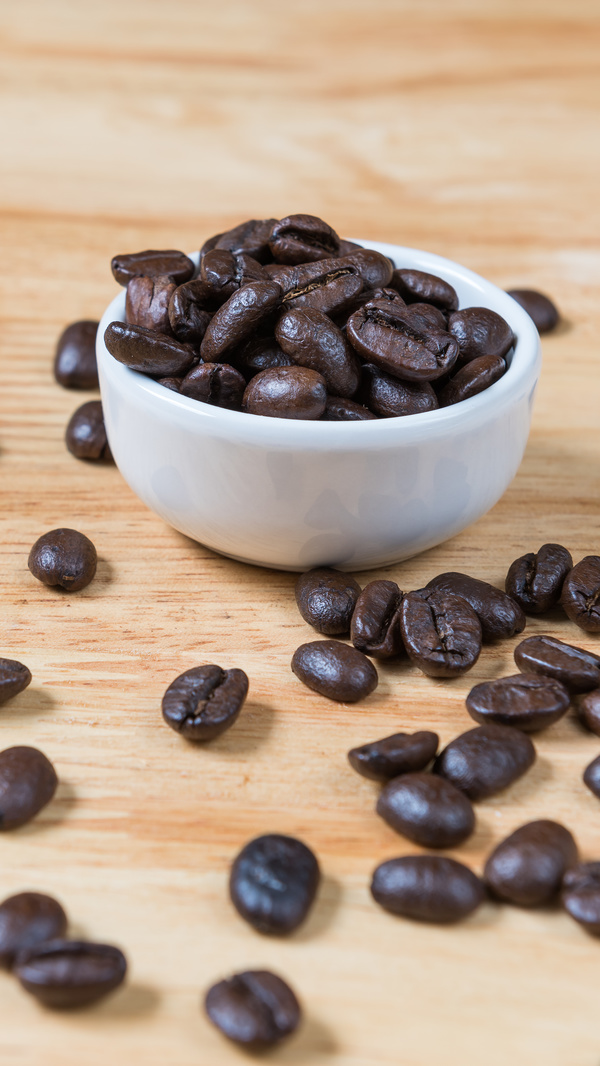 Wooden desktop with coffee beans and white bowl background