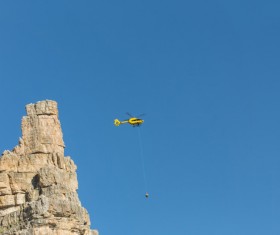 Yellow helicopter carrying loads in the Dolomites
