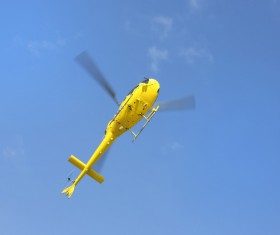 Yellow helicopter flying under blue sky Stock Photo 01
