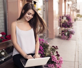 Young beautiful girl playing outdoors in the computer