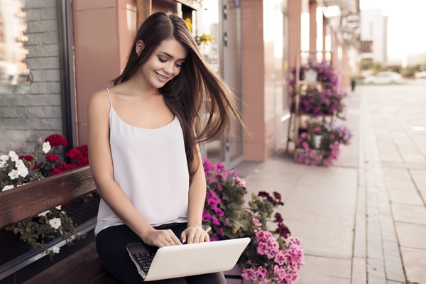 Young beautiful girl playing outdoors in the computer