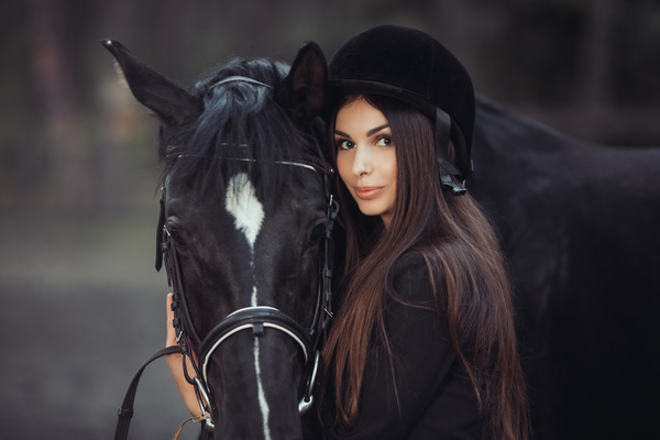 Young beautiful girl wearing a knight hat and dark horse