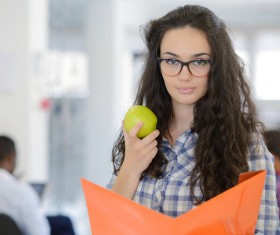 Young woman holding fruit and folder