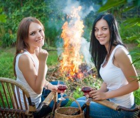 summer holidays and vacation - girls with red wine glasses near bonfire