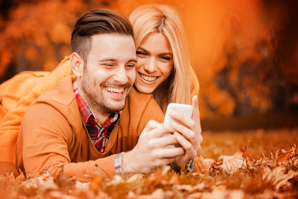 Couple looking at cell phone in autumn park Stock Photo