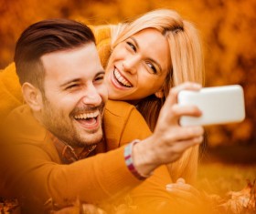Happy couple taking photos on cell phone Stock Photo