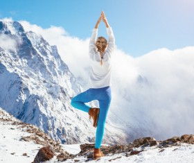 Snow-capped mountains do yoga women Stock Photo