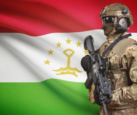 Flag of the Republic of Tajikistan and heavily armed soldiers