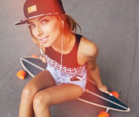 Sitting on the skateboard listening to music girl HD picture