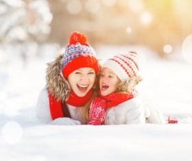 Smiling mother and daughter lying in the snow Stock Photo