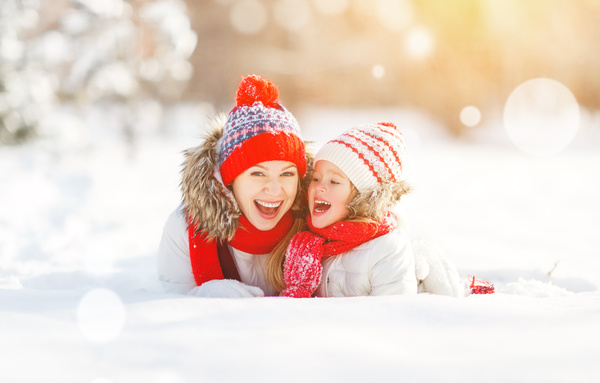 Smiling mother and daughter lying in the snow Stock Photo