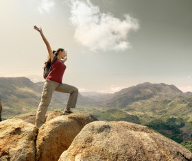 Standing woman cheering on high rocks HD picture