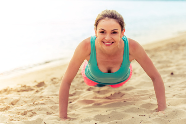 Woman doing push-ups on the beach Stock Photo