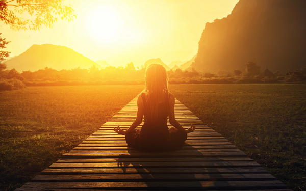 A woman meditating in the face of the sun Stock Photo