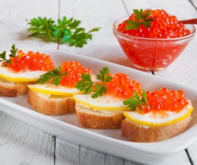 Bread red caviar with lemon and a bowl of red caviar
