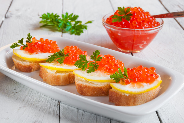 Bread red caviar with lemon and a bowl of red caviar