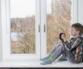 Children drinking coffee on the windowsill Stock Photo