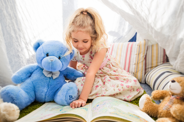 And teddy bears little girl reading a book together Stock Photo